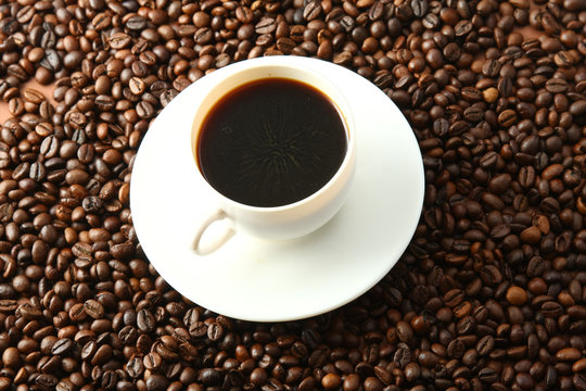 a cup of coffee on coffee beans, from above