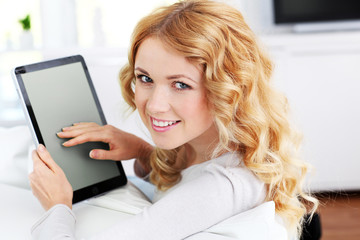 Blond woman relaxing in sofa using electronic tablet