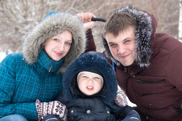 Obraz premium Family walking in the park during the winter snowfall