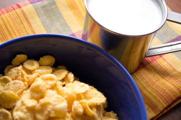 bowl of cornflakes on the table and a cup of milk