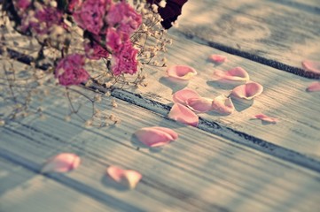 Pink rose petals and dry bouquet on white wood