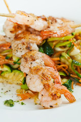 Shrimp on skewers on top of assortment of vegetables