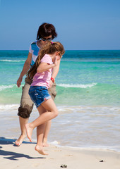 Naklejka premium mother and daughter play at the edge of the ocean