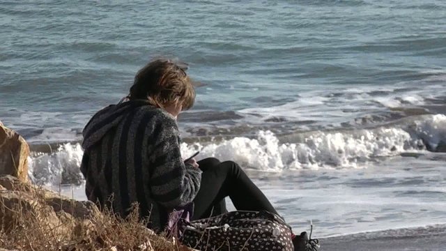 Chica escribiendo en la orilla del mar