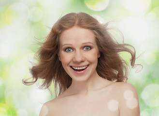 beautiful cheerful girl with flowing hair laughs on the green ba