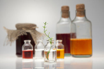 Small bottle with a green branch on a grey table