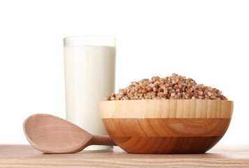Boiled buckwheat in a wooden bowl with a glass of milk