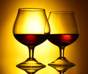 Two glasses of cognac on yellow background