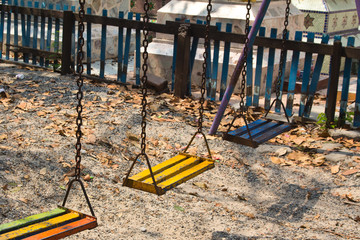 Empty baby swings on summer playground .