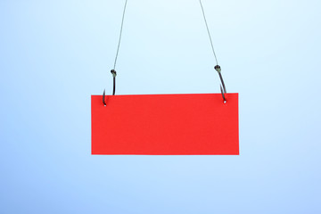 Empty sheet of a paper on fish hooks on blue background