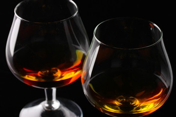 Two glasses of cognac on black background