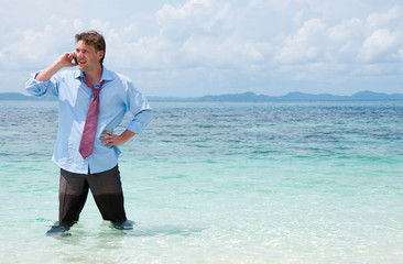 Business man calling by cell phone on the beach