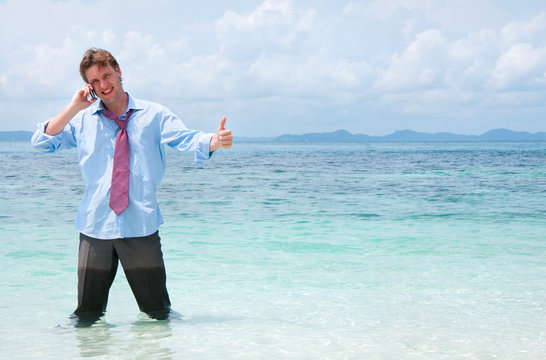 Business man calling by cell phone on the beach
