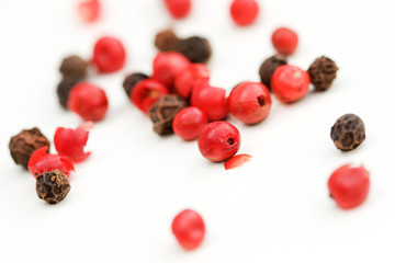 Red an black peppercorns on white background