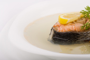 Tasty fish soup with salmon and lemon on a white background