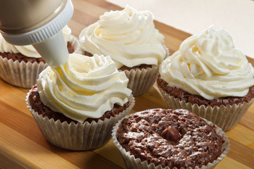 Decorating chocolate muffin with vanilla cream