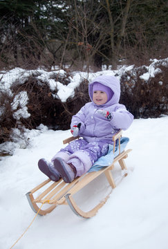 little girl in a winter park on a sled