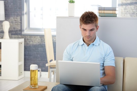 Young man with laptop and beer