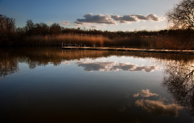 Fototapeta premium Beautiful late evening sunset landscape over jetty on lake