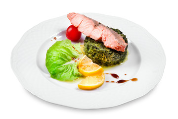 salmon with spinach garnish, cherry tomato, lemon slices on a pl
