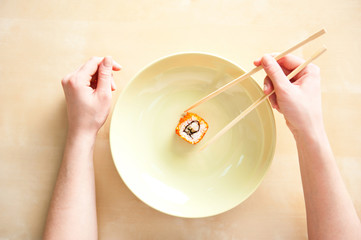 Woman holding sushi with chopsticks top view