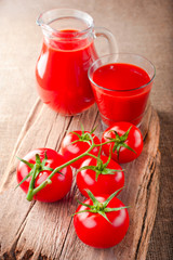 Tomato juice in jar and fresh tomatoes on wooden board