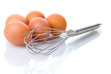 Metal whisk for whipping eggs and brown eggs isolated on white