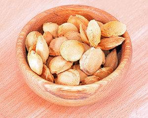Apricot stone in wooden bowl on wood background