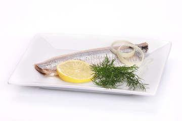 herring salt fillet with onion and lemon on white dish
