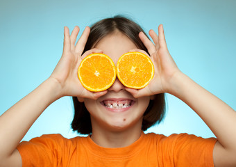Little girl using oranges as glasses