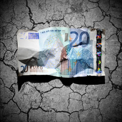 Crumpled 20 euro banknote on dry soil background