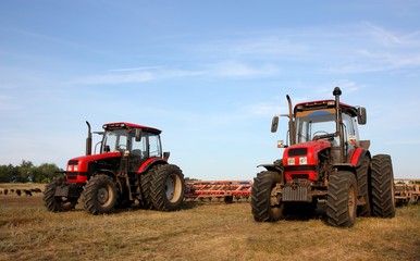 Two red tractors with a harrow