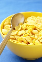corn flakes in a yellow bowl and a spoon