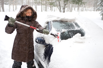Woman removing snow from car windshield