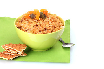 tasty cornflakes in bowl with dried fruits on green napkin