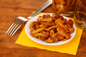 Marinated mushrooms in saucer on wooden table