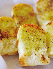 Garlic bread with herbs, on black bread dish.