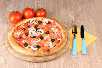 Aromatic pizza with vegetables on wooden background