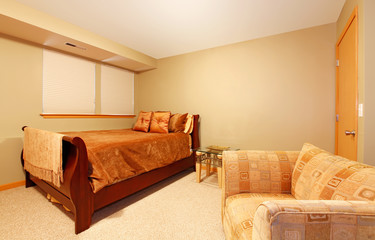 Simple basement level guest bedroom with bed and chair.
