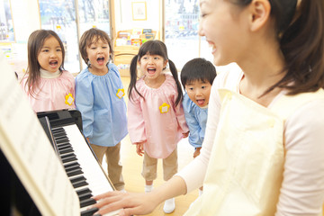 幼稚園教諭のピアノに合わせて歌う幼稚園児