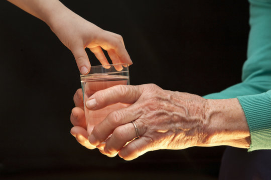 hands of grandmother and grandchild with the glass of water
