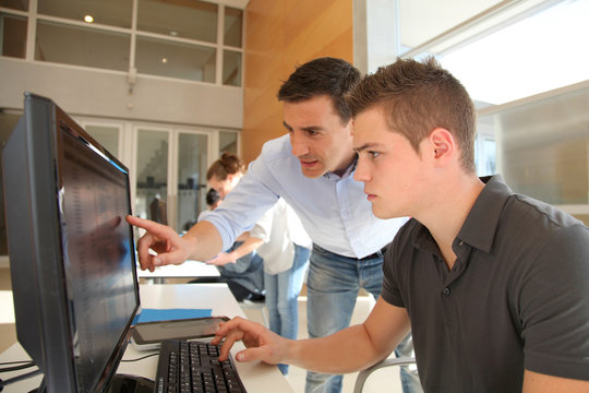 Teacher and student working on computer