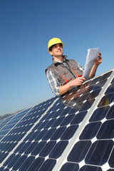 Man standing by solar panels with construction plan