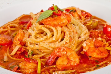 A plate of linguini with sauteed shrimp, tomato, chili  and oliv