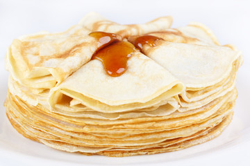 A stack of thin pancakes with honey