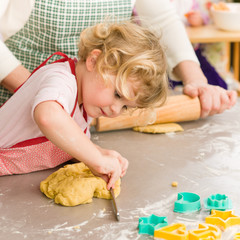 Obraz na płótnie Canvas Little girl cutting dough for cookies