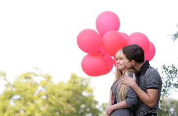 young loving couple with red balloons on natural background