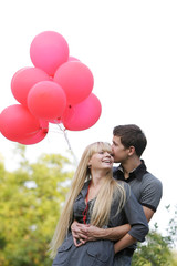 young loving couple with red balloons on natural background