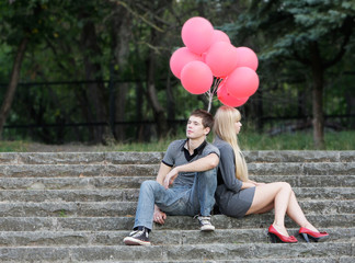 young couple with red balloons on natural background