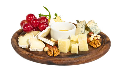 Various types of cheese with honey, nuts and grapes on plate, is